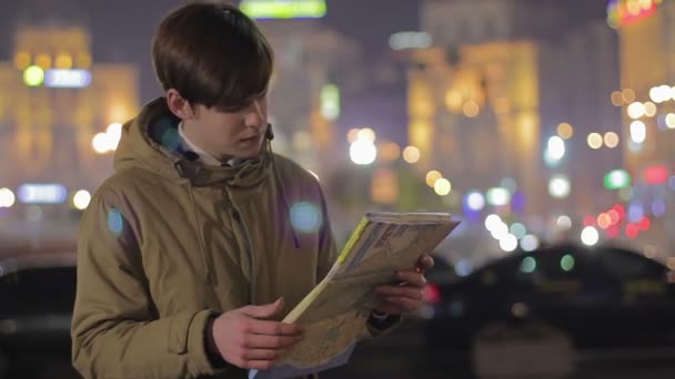 Mladý muž při pohledu na mapu a žádají kolemjdoucí pomoci najít cestu, turistika — Stock video