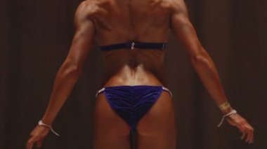 Profesyonel kadın vücut geliştirmeci fitness yarışmasında sırt kasları gösteren