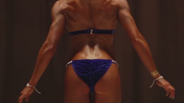 フィットネス競技で背中の筋肉を示すプロの女性ボディービルダー — ストック動画