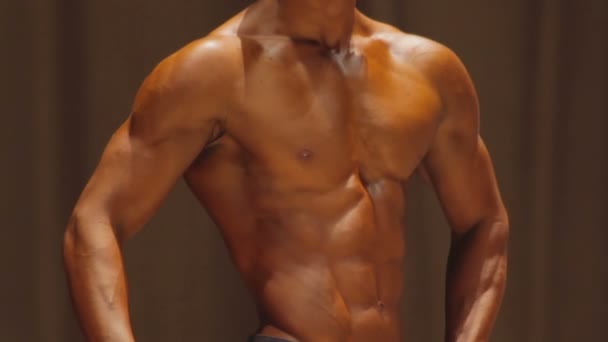 Сильный мужчина показывает идеальный мускулистый торс с идеальным прессом из шести упаковок на соревнованиях — стоковое видео
