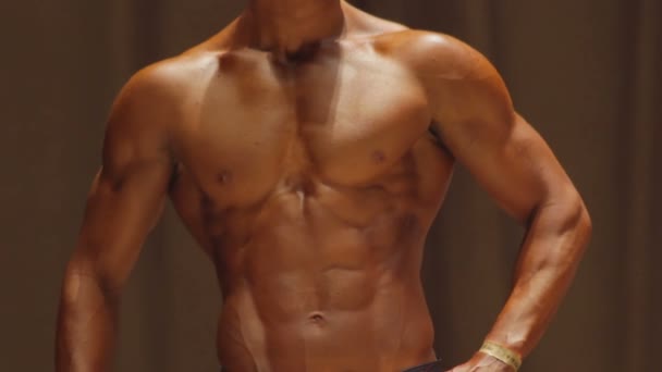 Fisiculturista masculino posando para demonstrar torso muscular perfeito com abdominais seis-pack — Vídeo de Stock