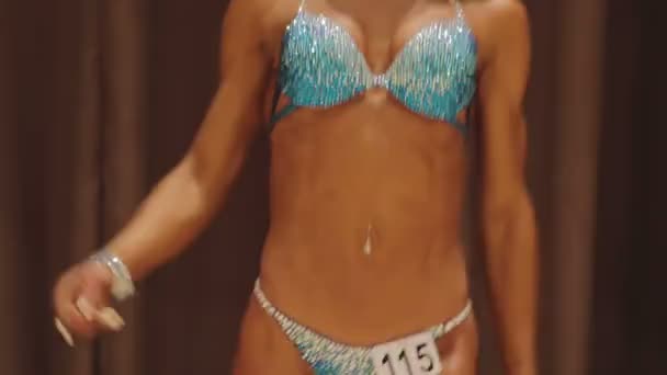Чарівна жіноча фітнес-модель м'яко рухається на сцені на змаганнях з бодібілдингу — стокове відео