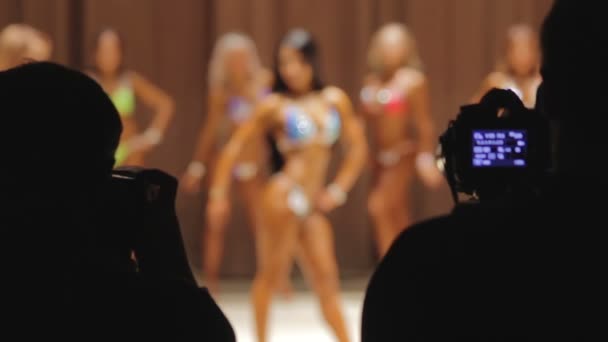 Silhouettes de personnes avec des caméras photographiant des femmes posant au concours de beauté — Video