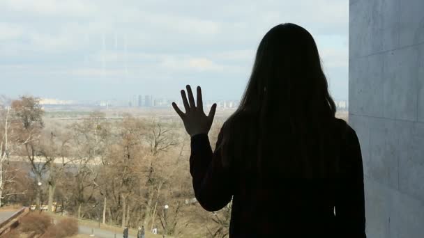 Deprimerade unga kvinna som tittar igenom det stora fönstret på vacker park — Stockvideo