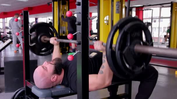 Stark idrottsman gör bänkpress övning, muskulös kroppsbyggare tränar i gym — Stockvideo