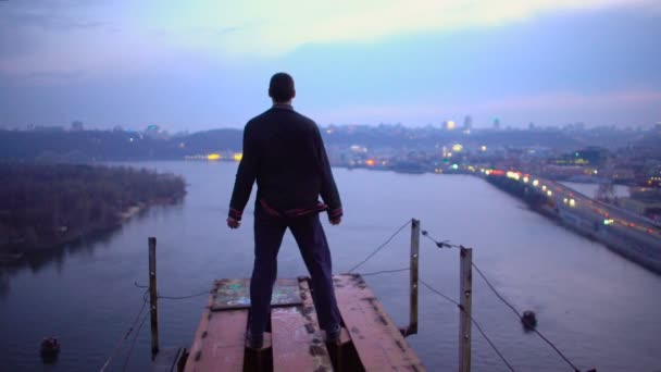 Храбрый человек, стоящий на краю недостроенного моста, свободы и вдохновения — стоковое видео