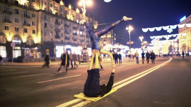 Woman and man doing acrobatic stunts in city center, evening time, extreme hobby — Stock Video