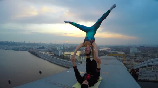 Uomo e donna che praticano yoga acrobatico in cima al ponte, sport pericolosi — Video Stock