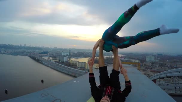 Pareja joven disfrutando de la adrenalina del yoga acrobático en la parte superior del puente alto — Vídeos de Stock