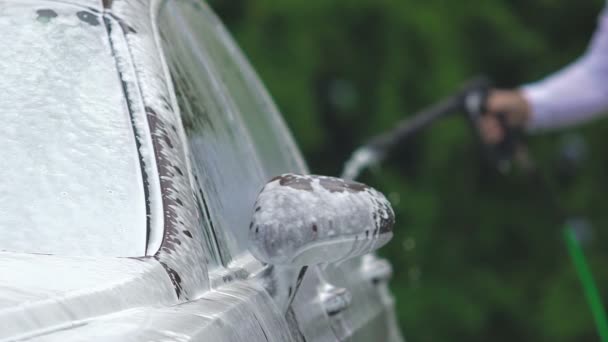 Lavado de coches empleado del negocio de limpieza de automóviles espumosos, rociando agua clara en la cabina — Vídeo de stock