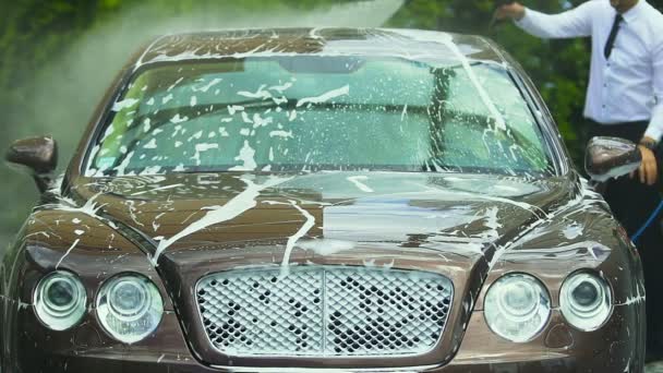 Businessman's driver washing luxury car with water spray gun for business trip — Stock Video