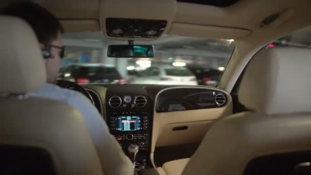Empresário dirigindo carro de luxo no estacionamento do prédio, vista do banco de trás — Vídeo de Stock