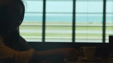 Cep telefonundan mesaj yazarak Havaalanı kafede kahve içme genç gülümseyen kadın