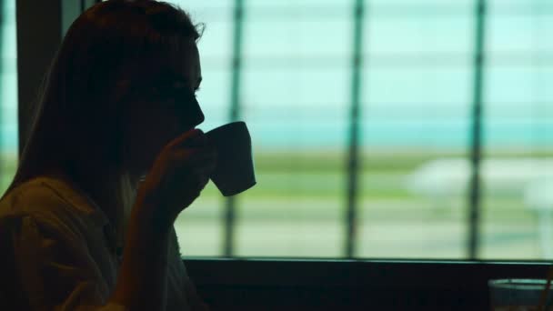 Jovencita sentada en el restaurante del aeropuerto y disfrutando de café caliente, turismo — Vídeo de stock