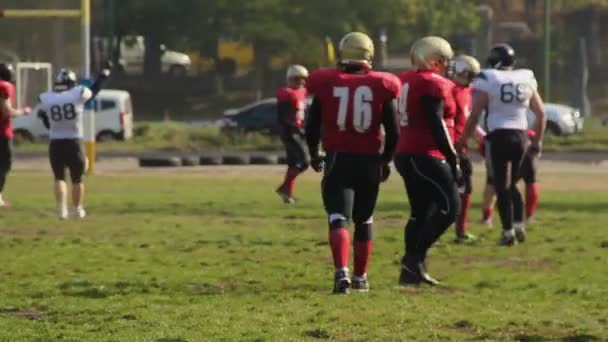 Jugadores de fútbol americano activo cambiando de bando durante el partido, partido amateur — Vídeos de Stock