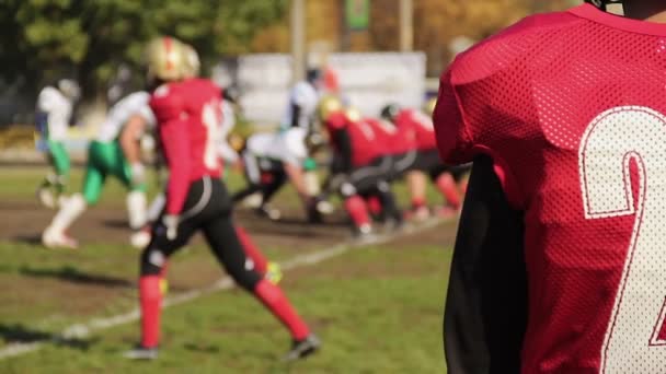 Angelägen fotbollsspelare titta på spelet, oskärpa rivaliserande lag kämpar för bollen — Stockvideo