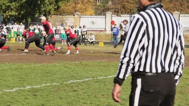 Árbitro supervisando partido de fútbol americano, jugadores tomando posiciones antes de encajar — Vídeo de stock
