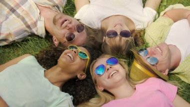 İnsanlar, çim üzerinde yalan hayattan zevk ve gülüyor, gökyüzü güneş gözlüğü yansıması