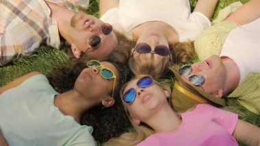 Mutlu insanlar daire park ve şarkıları söyleyerek, çim üzerinde yalan eğleniyor