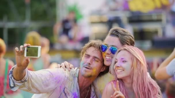 Emocionados jóvenes con caras cubiertas de colores, amigos sonriendo para la cámara — Vídeos de Stock