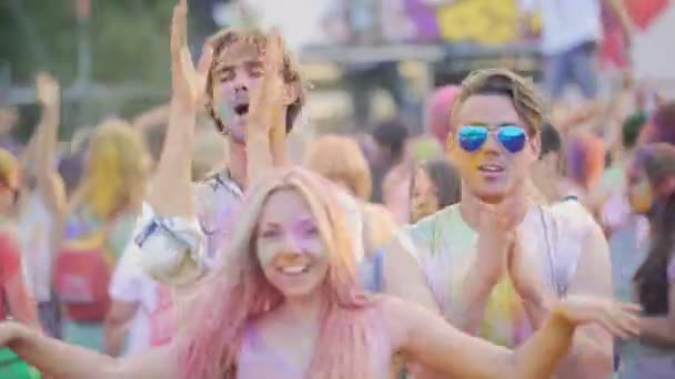 Positieve emoties van happy mannelijke en vrouwelijke vrienden knuffelen op kleur festival — Stockvideo
