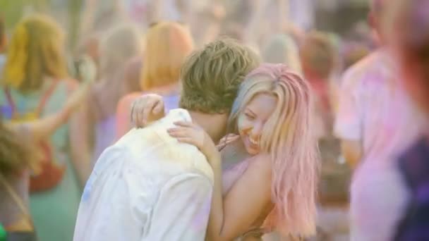 Pareja feliz abrazando, coqueteando y bailando en multitud en el festival de color al aire libre — Vídeos de Stock