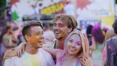Mutlu arkadaşlar renk festivalinde dışarı asılı, romantik çift sarılma ve dans