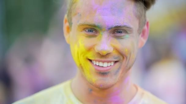 Gelukkig knappe man glimlachend naar camera, genietend van sfeer op kleur Festival — Stockvideo