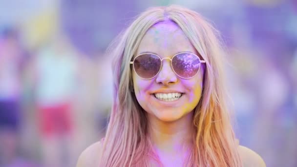 Girl in sunglasses covered in colorful dyes smiling, blowing air kiss to camera — Stock Video