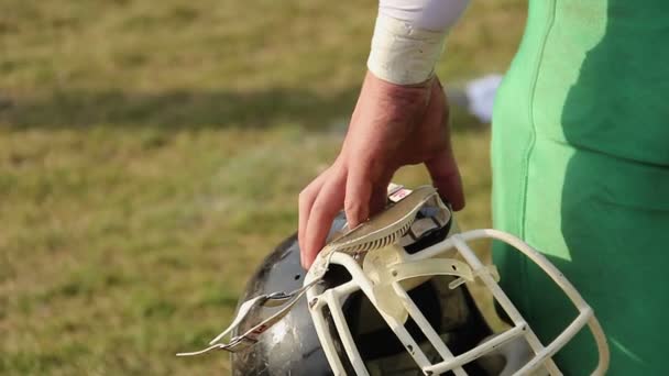 Jogador segurando capacete, assistindo jogo de futebol americano, à espera de intercâmbio — Vídeo de Stock