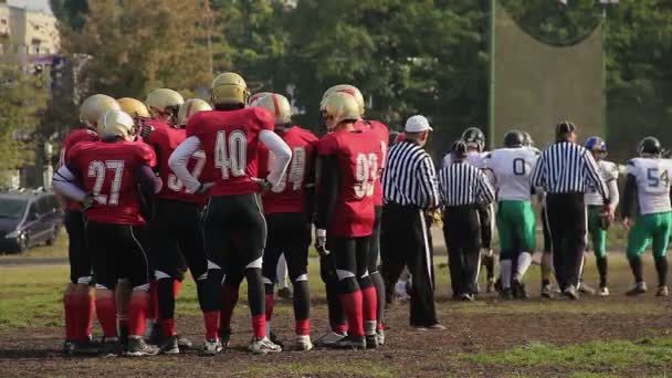 Equipo discutiendo estrategia de juego de fútbol americano, jugadores de pie en el terreno de juego — Vídeo de stock