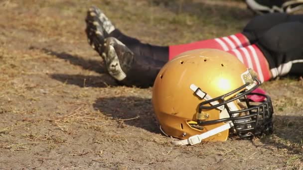Voetbal speler benen en helm close-up, atleet onder rest over stadion veld — Stockvideo