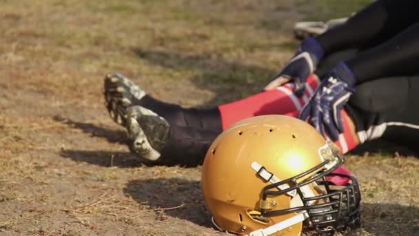 Amerikansk fotbollsspelare sitter på planen, med resten efter hård träning — Stockvideo