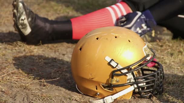 Jugador de fútbol profesional sentado en el campo durante el tiempo de espera, primer plano casco — Vídeo de stock