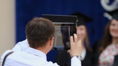 Mutlu baba mezuniyet töreninde kızı resim çekmek için Tablet Pc kullanma