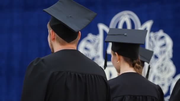 Emocionados hombres y mujeres jóvenes escuchando el discurso en la ceremonia de entrega de diplomas — Vídeos de Stock