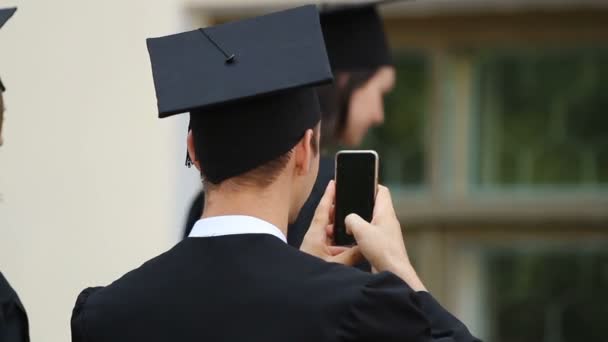 Estudiante masculino tomando muchas fotos de amigos, ceremonia de graduación, juventud feliz — Vídeos de Stock