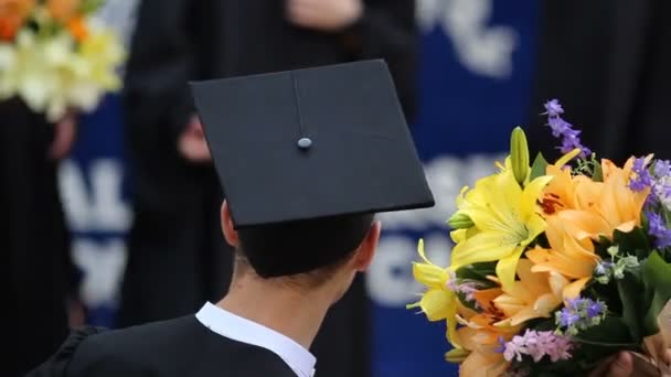 Graduados alegres bromeando y divirtiéndose después de la ceremonia para recibir diplomas — Vídeos de Stock