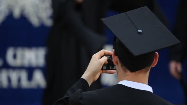Mannelijke afgestudeerde in academische jurk nemen foto van vrienden ontvangen diploma 's — Stockvideo