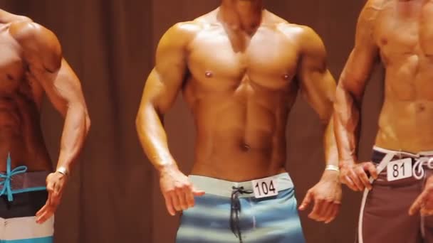 Tiefgebräunte Jungs, die starke perfekte Körper auf der Bühne demonstrieren, Sportwettkampf — Stockvideo
