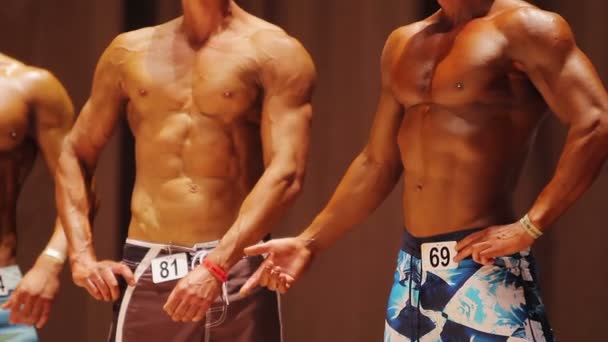 Two deep tanned men taking relaxed pose at bodybuilding show, professional sport — Stock Video