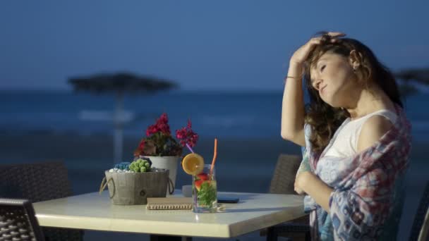 Jolie femme réfléchie dégustant un cocktail au restaurant en bord de mer, humeur romantique — Video