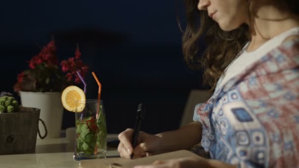 Hermosa joven escribiendo pensamientos románticos en el diario con sonrisa en la cara — Vídeos de Stock