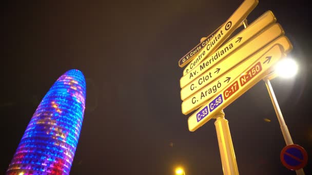 Rascacielos iluminado Torre Agbar, letreros que indican nombres de calles para turistas — Vídeo de stock