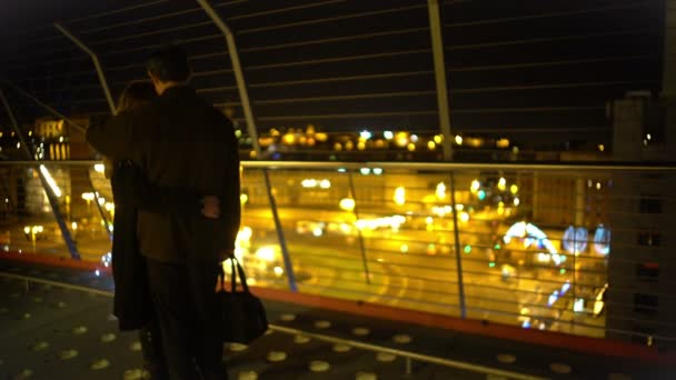 Feliz pareja casada abrazándose en la parte superior del rascacielos, mirando las luces nocturnas de la ciudad — Vídeos de Stock