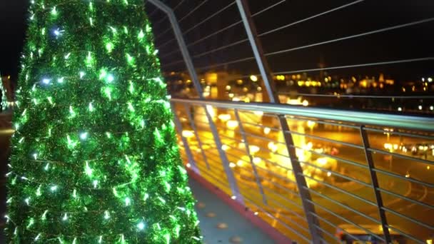 Bonito árbol de Navidad iluminado en la parte superior del rascacielos, luces de la ciudad de noche festiva — Vídeo de stock