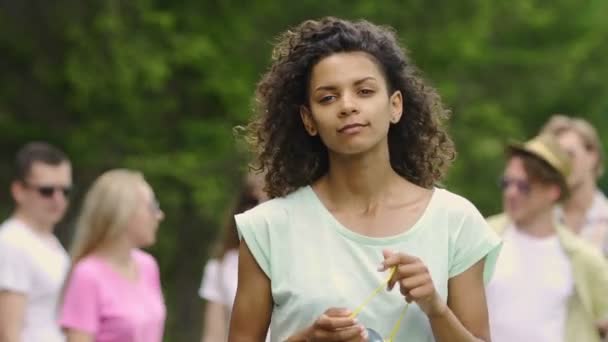 Joven hermosa chica de pie en el parque y mirando a la cámara, ternura — Vídeo de stock