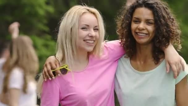 Дві молоді красиві багаторасові жінки обіймаються і посміхаються камері, дружба — стокове відео