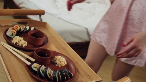 Kvinna kommer partner med sushi rullar i sängen — Stockvideo