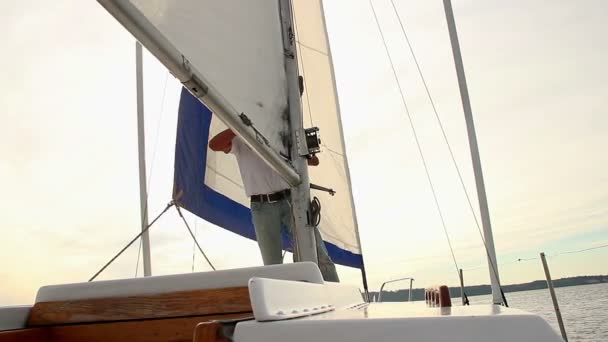 Homme soulevant la grand-voile sur le bateau — Video